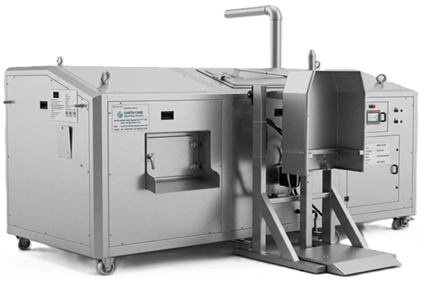 Large stainless steel industrial processing unit with control panel, hopper and angled chute on a wheeled base of casters.