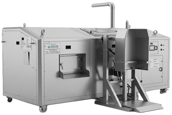 Large stainless steel industrial processing machine with a top chute, control panels, and a loading platform on a wheeled base.